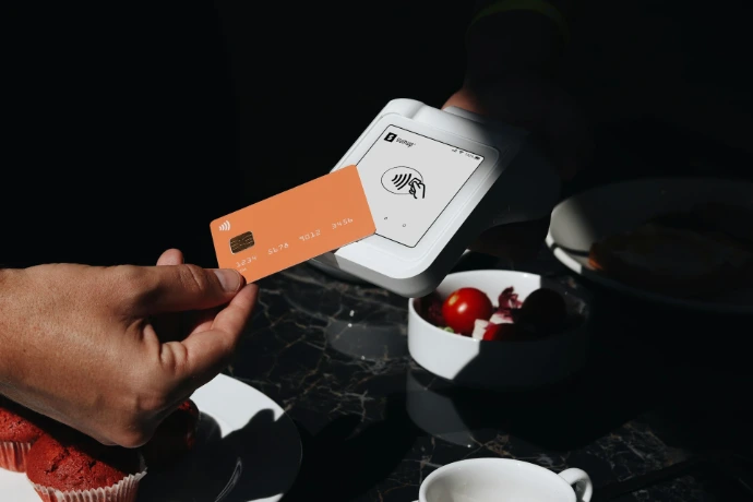 A person holding a credit card over a plate of food